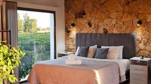 a bedroom with a large bed with a stone wall at Rincon del Malbec in Ciudad Lujan de Cuyo +38 photos