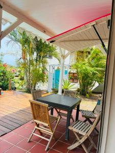 a patio with a table and chairs on a deck at Villa Piscine - Maracudja in Les Anses-dʼArlets