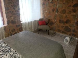a bedroom with a bed and a red pillow and a chair at Posada Valentina in San Salvador de Jujuy