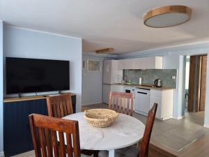 a kitchen and dining room with a table and a television at Apartament "Przez las na plażę" in Świnoujście