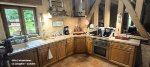 a large kitchen with wooden cabinets and a sink at La Longère en Puisaye, 2 gîtes à 10 min de Guédelon réservables ensemble et séparément in Dampierre-sous-Bouhy