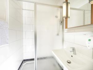 a white bathroom with a shower and a sink at ibis Leipzig Nord-Ost in Leipzig +40 photos