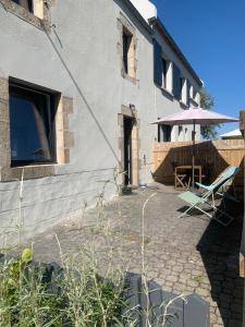 a house with a patio with a table and an umbrella at Ti Bihan in Plouguerneau