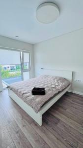 a white bedroom with a bed with a black bag on it at Ungura Nord in Mozūriškiai