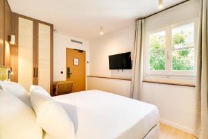 a bedroom with a white bed and a window at Hotel Murmures Notre-Dame in Paris