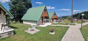 a house with a green roof and a yard at Durmitor Bungalows in Žabljak