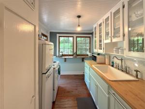 a kitchen with a white refrigerator and a sink at Cricket Cottage in Eureka Springs
