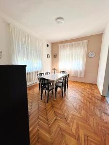 a dining room with a table and chairs on a wooden floor at L&M Apartman in Virje