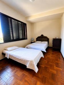 two beds in a room with two windows at Casa aconchegante in Teresópolis