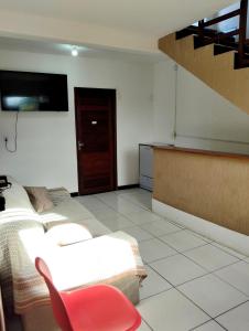 a living room with a bed and a red chair at Pousada dos Marujos in Pipa