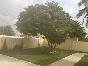 a tree in a yard next to a fence at The Vicarage in Lashibi