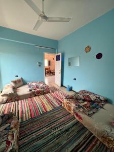two beds in a room with blue walls and a rug at Nubian Kingdom Aragheed House in Aswan
