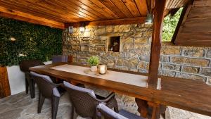 a wooden table and chairs in a stone wall at Къща за гости Хитър Петър in Apriltsi