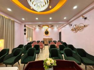 a conference room with green chairs and a chandelier at Hotel Buddha International in Patna
