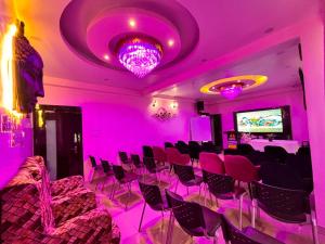 a room with pink lights and chairs and a tv at Hotel Buddha International in Patna