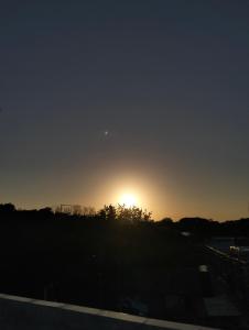 a sunset over a field with the sun in the sky at Pousada dos Marujos in Pipa +6 photos