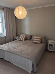 a bedroom with a large bed and a chandelier at Fjallbacka, Modern nyproducerad lägenhet med egen parkering och laddning in Fjällbacka +11 photos