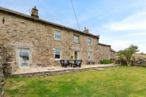 an old stone house with a patio and grass at 4 Bed in Low Row oc-h34097 in Gunnerside