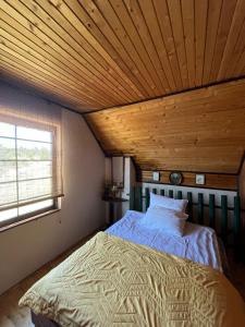 a bed in a room with a wooden ceiling at Meandri Ćehotine in Pljevlja