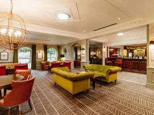 a lobby with yellow couches and a bar at Mercure Haydock Hotel in Haydock