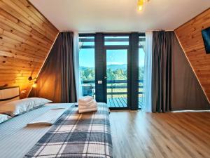 a bedroom with a bed and a large window at Cabana Magia Muntelui in Prisaca Dornei
