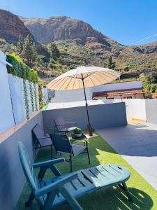 a patio with a table and chairs and an umbrella at Chalet Rutas de Valsequillo in Valsequillo