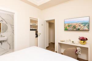 a white bedroom with a bed and a desk at Monastero San Pietro Claver in Rome