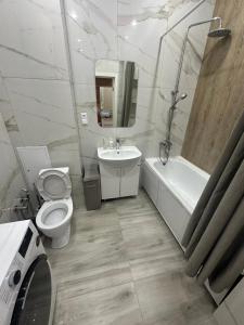 a white bathroom with a toilet and a sink at Dostar Apartments in Karagandy