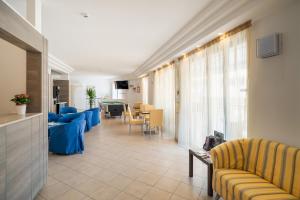 a living room with blue couches and a dining room at Hotel Palladio in Caorle