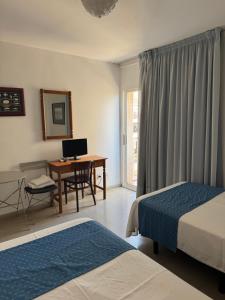 a hotel room with two beds and a desk with a computer at Plaça Vella in Sant Carles de la Ràpita +8 photos