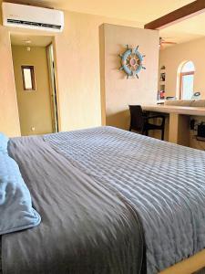 a bedroom with a bed and a desk with a clock on the wall at Tranquilidad Total Frente al Mar I 3 Hab y Alberca in Barra de Potosi