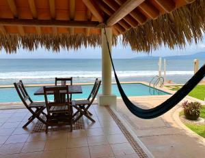 a patio with a hammock and a table and chairs and the ocean at Tranquilidad Total Frente al Mar I 3 Hab y Alberca in Barra de Potosi