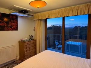 a bedroom with a bed and a large window at Orchard Manor in Probus
