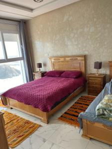 a bedroom with a large wooden bed with purple sheets at Goldenbeachhouse in Mirleft