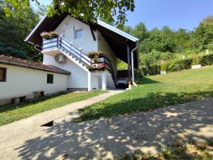 a white house with a balcony with flowers on it at Apartmani KOSMOS in Rudnik