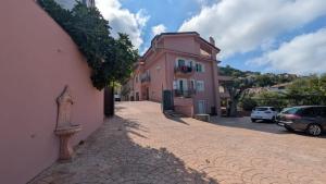 a brick street with a pink building and cars parked at Grecale in Centola