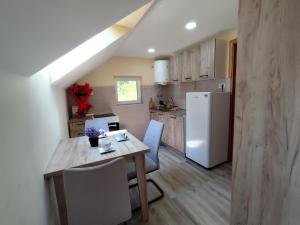 a kitchen with a wooden table and a white refrigerator at Apartmani KOSMOS in Rudnik