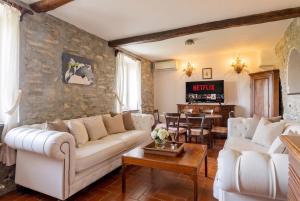 a living room with white furniture and a stone wall at Villa with Pool e Jacuzzi Free Parking AC in San Lorenzo della Costa