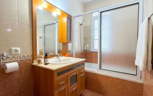 a bathroom with a sink and a shower with a mirror at Vila Boehémia in Canhas