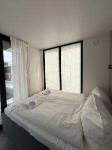 a white bed in a bedroom with two windows at Design-Hausboot am Rheinsteig in Lorch am Rhein