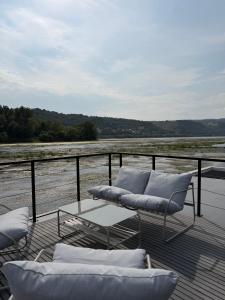 a deck with two chairs and a couch on a balcony at Design-Hausboot am Rheinsteig in Lorch am Rhein