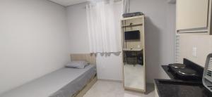 a small white room with a bed and a mirror at Studio 1 in Jundiaí