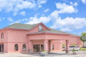 a pink building with a blue sky in the background at Oasis Inn in San Angelo
