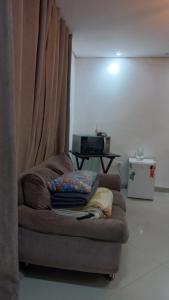 a couch sitting in a living room next to a curtain at suite Perto do aeroporto de guarulhosAv Jovita 401 in Guarulhos +2 photos