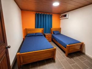 two beds in a small room with blue sheets at Villa Edallys in Capira