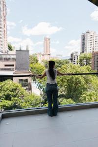 a woman standing on a balcony looking out at a city at Altitud Medellín Viem Living in Medellín