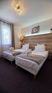 a hotel room with two beds with stuffed animals on them at Hôtel Le Pommeil in Guéret