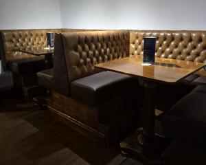 a booth in a restaurant with a table and chairs at The Crewe Arms Hotel in Crewe