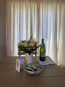 a bottle of wine and a vase of flowers on a table at 2 Bedroom sea view studio in Onrus in Hermanus