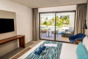 a hotel room with a bed and a flat screen tv at Majestic Elegance Costa Mujeres - All Inclusive in Cancún